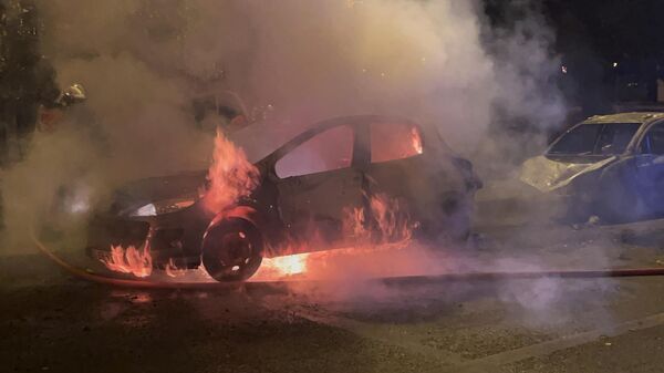 Горящий автомобиль во время беспорядков во французском Нантере