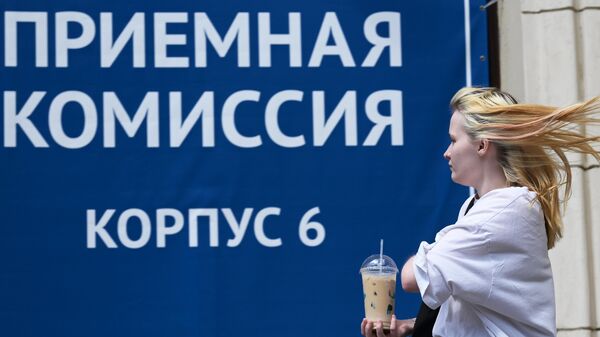 Девушка проходит мимо баннера приемная комиссия на фасаде РГГУ в Москве 