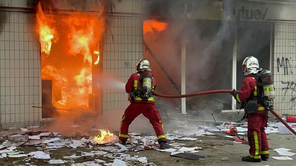 Сотрудники пожарной службы тушат пожар в одном из зданий во время беспорядков во французском Нантере