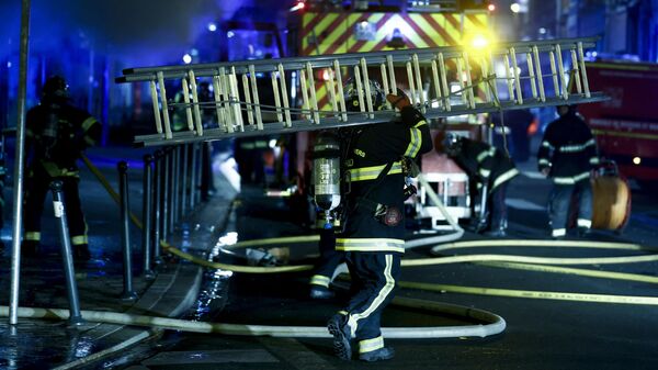 Пожарные идет с пожарной лестницей после тушения пожара в отеле во время протестов в Рубе, на севере Франции, 30 июня 2023 года