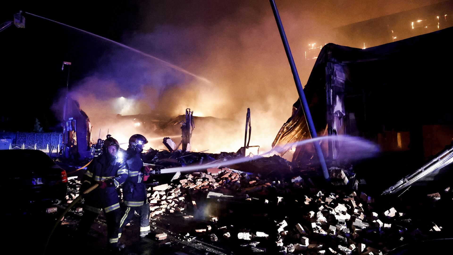 Пожарные тушат пламя здания, подожженного во время протестов в Рубе, на севере Франции, 30 июня 2023 года - РИА Новости, 1920, 30.06.2023