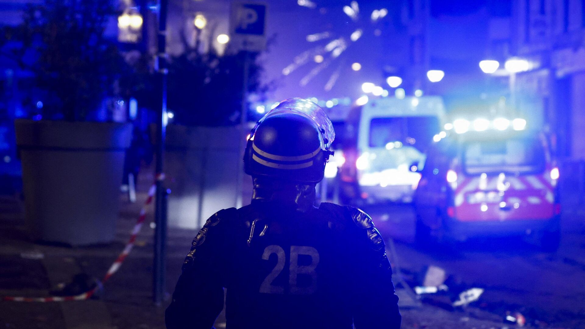 Полицейский наблюдает за взрывом фейерверков во время протестов в Рубе, на севере Франции, 30 июня 2023 года - РИА Новости, 1920, 30.06.2023