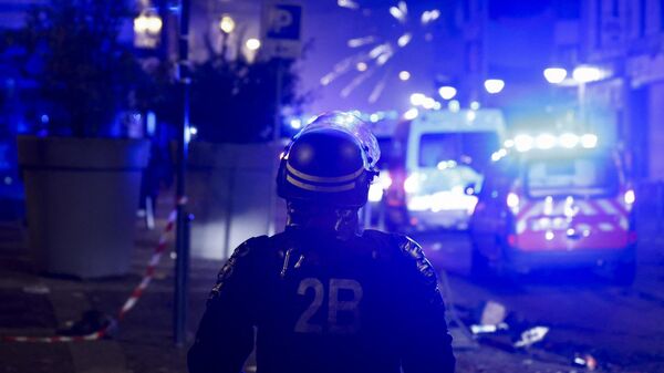 Полицейский наблюдает за взрывом фейерверков во время протестов в Рубе, на севере Франции, 30 июня 2023 года
