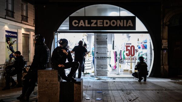 Полицейские ждут перед разграбленным магазином, патрулируя улицы Лиона во время протестов, 30 июня 2023