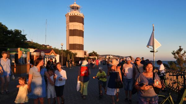 Люди гуляют возле Анапского маяка на берегу Чёрного моря