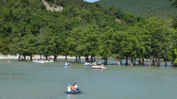 Люди купаются и плывут на лодках в кипарисовом озере в поселке Сукко