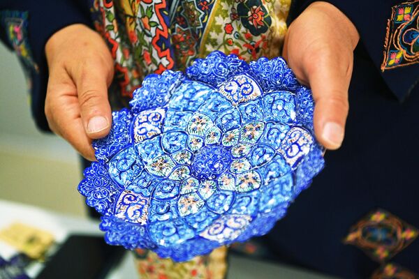Участница выставки демонстрирует тарелку с ручной росписью на одном из стендов на выставке иранского искусства в рамках проекта Обменные культурные мероприятия России и Ирана на ВДНХ
