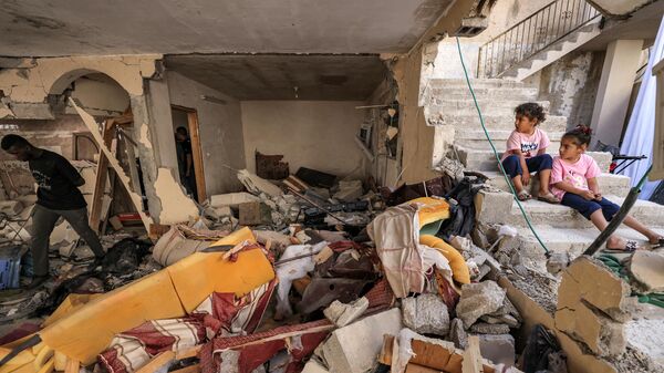 Дети сидят на лестнице среди обломков и сломанной мебели разрушенной квартиры в здании в оккупированном городе Дженин