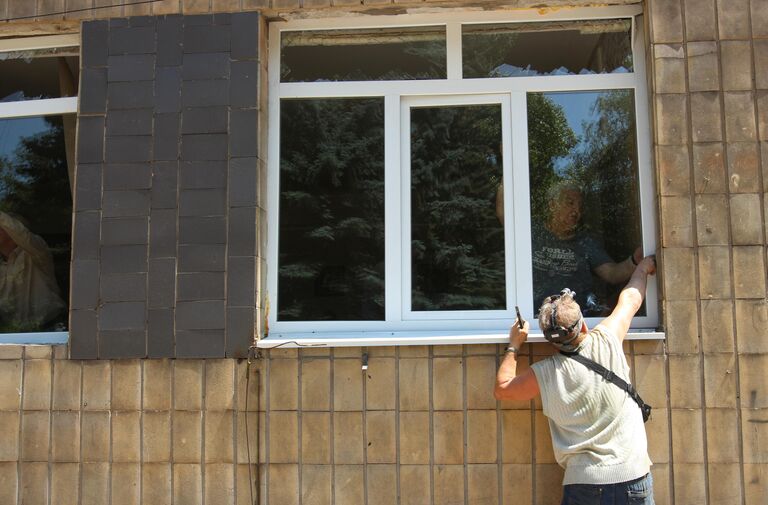 Мужчины вставляют новые окна в городской больнице, пострадавшей в результате обстрела ВСУ города Макеевки