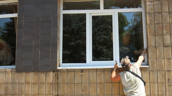 Мужчины вставляют новые окна в городской больнице, пострадавшей в результате обстрела ВСУ города Макеевки