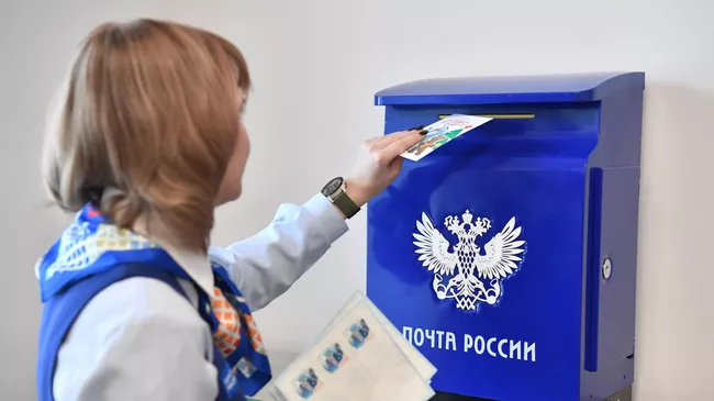Девушка опускает письмо в почтовый ящик 
