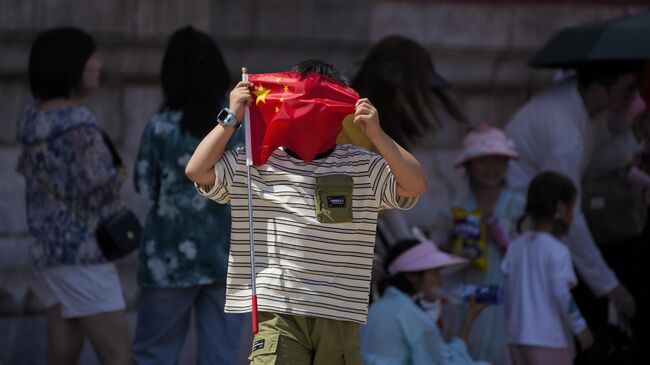 Мальчик держит китайский флаг в очереди возле входа в Запретный город в Пекине