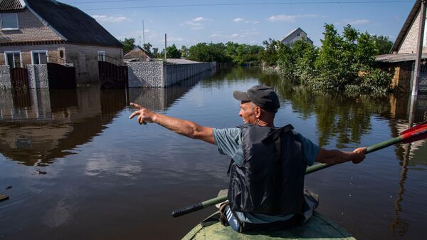 Мужчина плывет на лодке по селу Корсунка Новокаховского района Херсонской области, затопленному водой после разрушения Каховской ГЭС