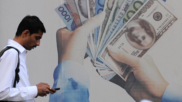 Прохожий проверяет свой мобильный телефон возле банка, предлагающего курсы обмена иностранной валюты, в Мумбае