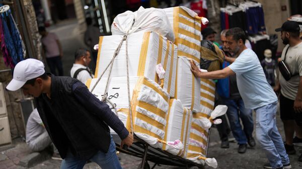 Мужчины тянут тележку с товарами на уличном рынке в Стамбуле, Турция