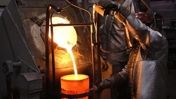 Металлурги наливают в тигель расплавленное золото высшей пробы для производства слитков 99,99 процентов чистоты