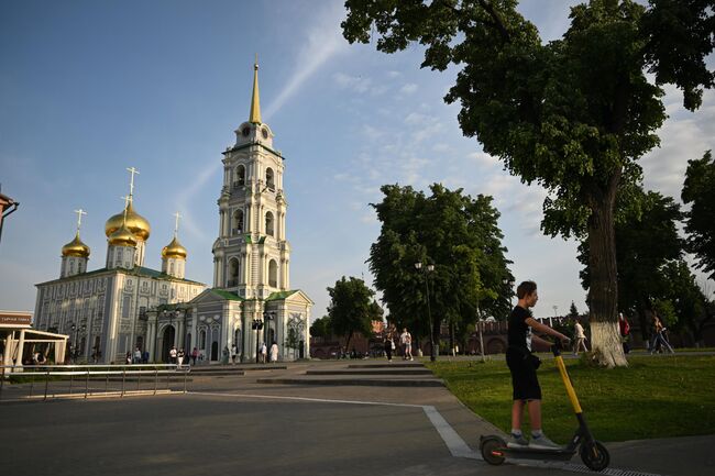 Молодой человек катается на самокате на территории Тульского Кремля. На заднем плане - Свято-Успенский собор и Соборная колокольня Молодой человек катается на самокате на территории Тульского Кремля. На заднем плане - Свято-Успенский собор и Соборная колокольня