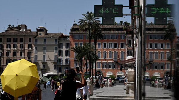 Люди проходят мимо табло с показанием температуры воздуха в Риме