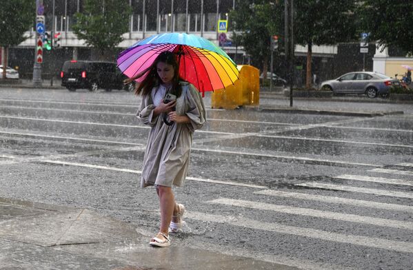 Девушка переходит дорогу во время дождя в Москве