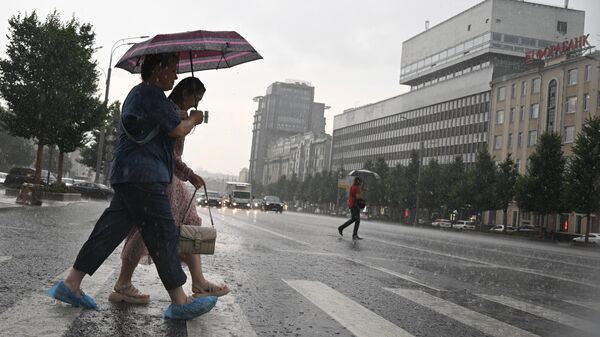 Люди переходят дорогу во время дождя в Москве