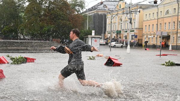 Мужчина на подтопленной улице в результате ливня в Москве