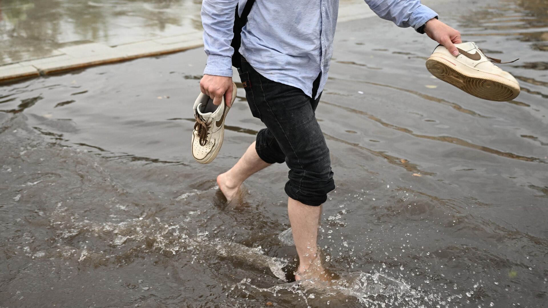 Прохожий идет по подтопленной улице, сняв свою обувь - РИА Новости, 1920, 23.08.2023