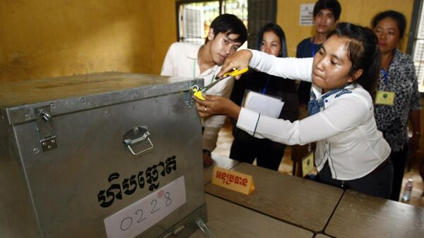 Представитель избирательной комиссии открывает урну для подсчета голосов на избирательном участке в  Пномпене в Камбодже