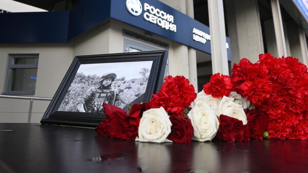 Фотография погибшего военкора РИА Новости Ростислава Журавлева и цветы перед зданием международного информационного агентства Россия сегодня