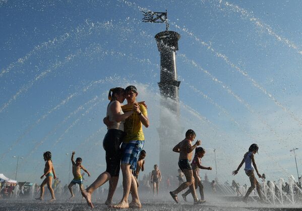 Молодые люди танцуют в фонтане в парке 300-летия Санкт-Петербурга