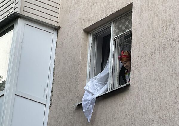 Женщина в окне жилого дома на одной из улиц Таганрога,  стекла которого выбило после взрыва