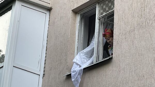 Женщина в окне жилого дома на одной из улиц Таганрога,  стекла которого выбило после взрыва