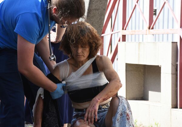 Медицинский сотрудник оказывает помощь женщине, раненной в результате обстрела Донецка со стороны ВСУ