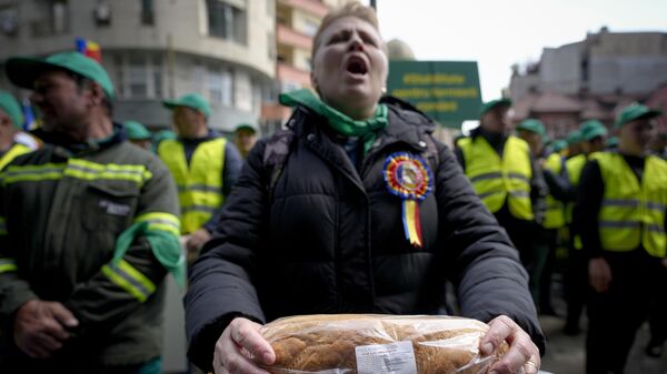 Женщина c буханкой хлеба в руках во время протеста фермеров перед офисом Европейской комиссии