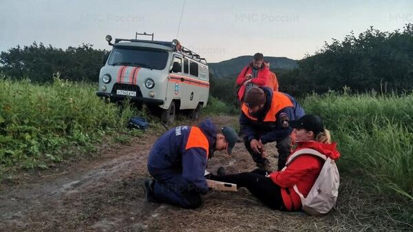 Спасатели оказывают помощь женщине, которая травмировала ногу при спуске с вулкана Эбеко
