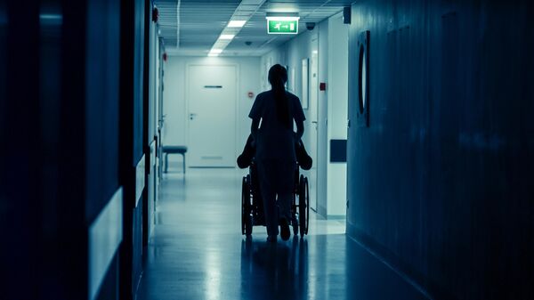 Медсестра с пациентом в коридоре больницы