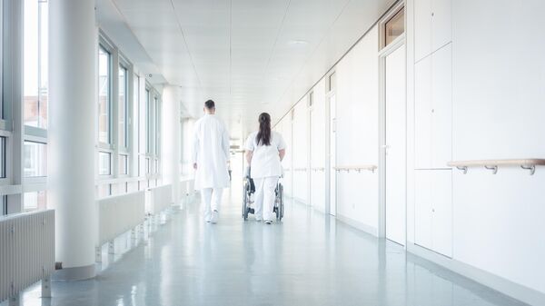 Врач и медсестра с пациентом в коридоре больницы