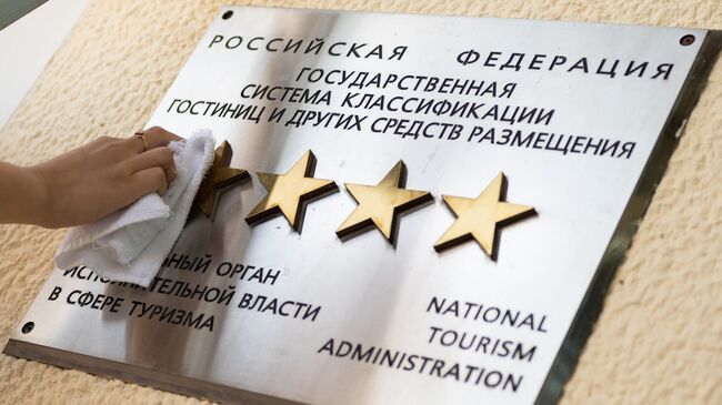 Сотрудница санатория в Сочи чистит табличку звездности на здании отеля