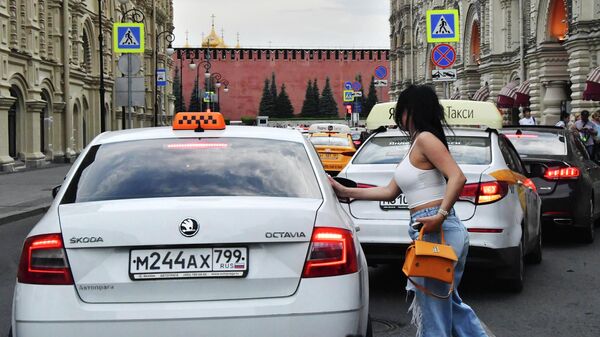 Девушка у машины такси на улице Ильинке в Москве