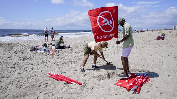 Установка красного флага, предупреждающего посетителей о запрете купания на пляже, Нью-Йорк