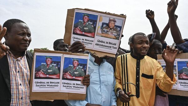 Сторонники Национального совета Нигера по охране родины (CNSP) держит плакат с фотографией генерала Абдурахамана Тиани в Ниамее