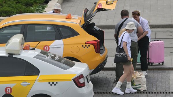 Пассажиры с багажом и автомобили такси возле Павелецкого вокзала в Москве