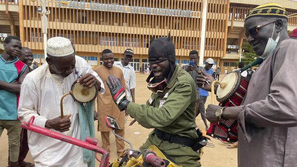 Сторонники Национального совета по защите отечества играют на музыкальных инструментах в Ниамее, Нигер