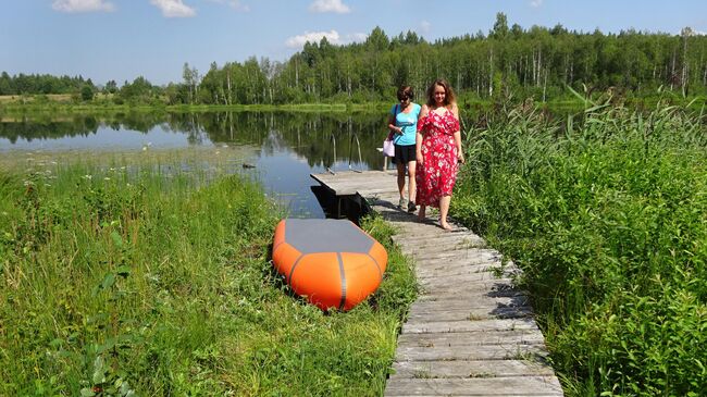 Озеро Мериново, мостки в арт-кластере Мериново и его хозяйка Валерия Лебедева (в платье) с гостьей