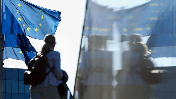 Женщина проходит мимо флагов ЕС в Брюсселе