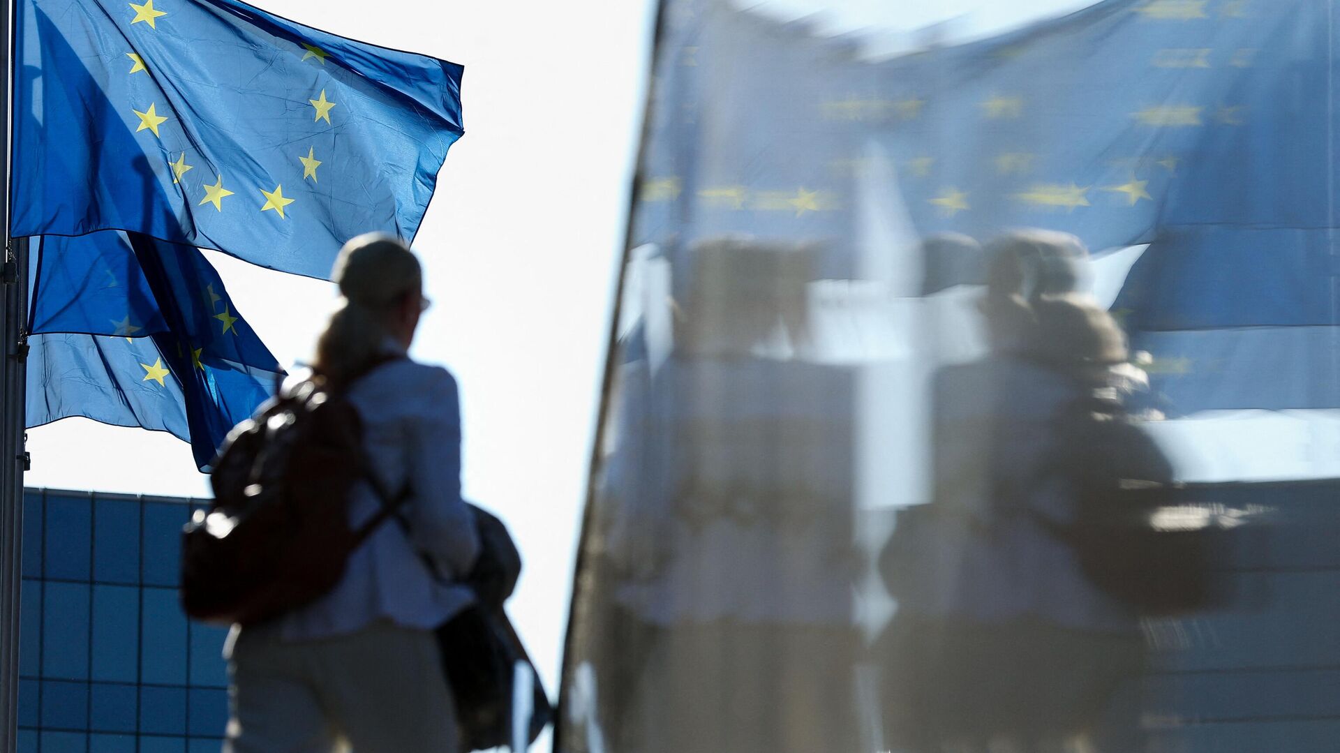 Женщина проходит мимо флагов ЕС в Брюсселе - РИА Новости, 1920, 12.08.2023