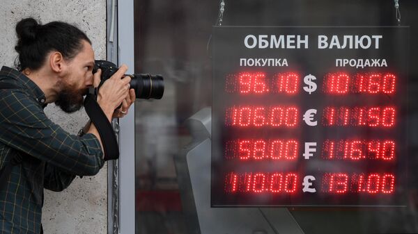Мужчина фотографирует электронное табло у пункта обмена валют в Москве