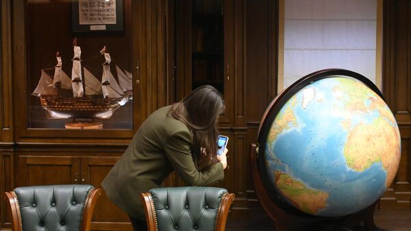 Девушка фотографирует глобус в штаб-квартире Русского географического общества в доходном доме Московского купеческого общества