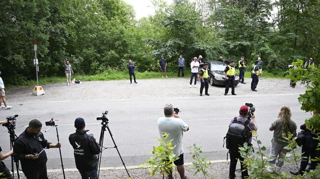 Беженец Салван Момика держит Коран стоя в окружении полиции и журналистов около посольства Ирана в Лидинге, Швеция