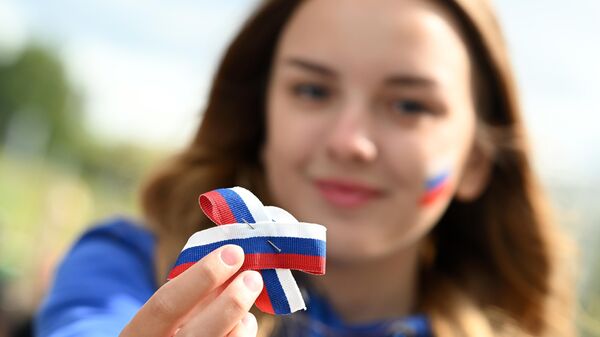 Волонтеры Молодая гвардия раздают ленточки в день празднования российского флага в Казани