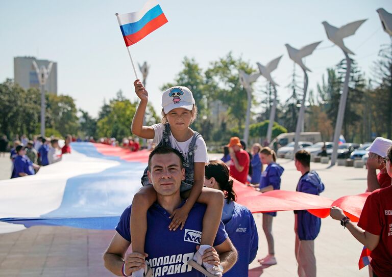 Участники праздничных мероприятий, приуроченных ко Дню российского флага, на площади Ленина в Мариуполе